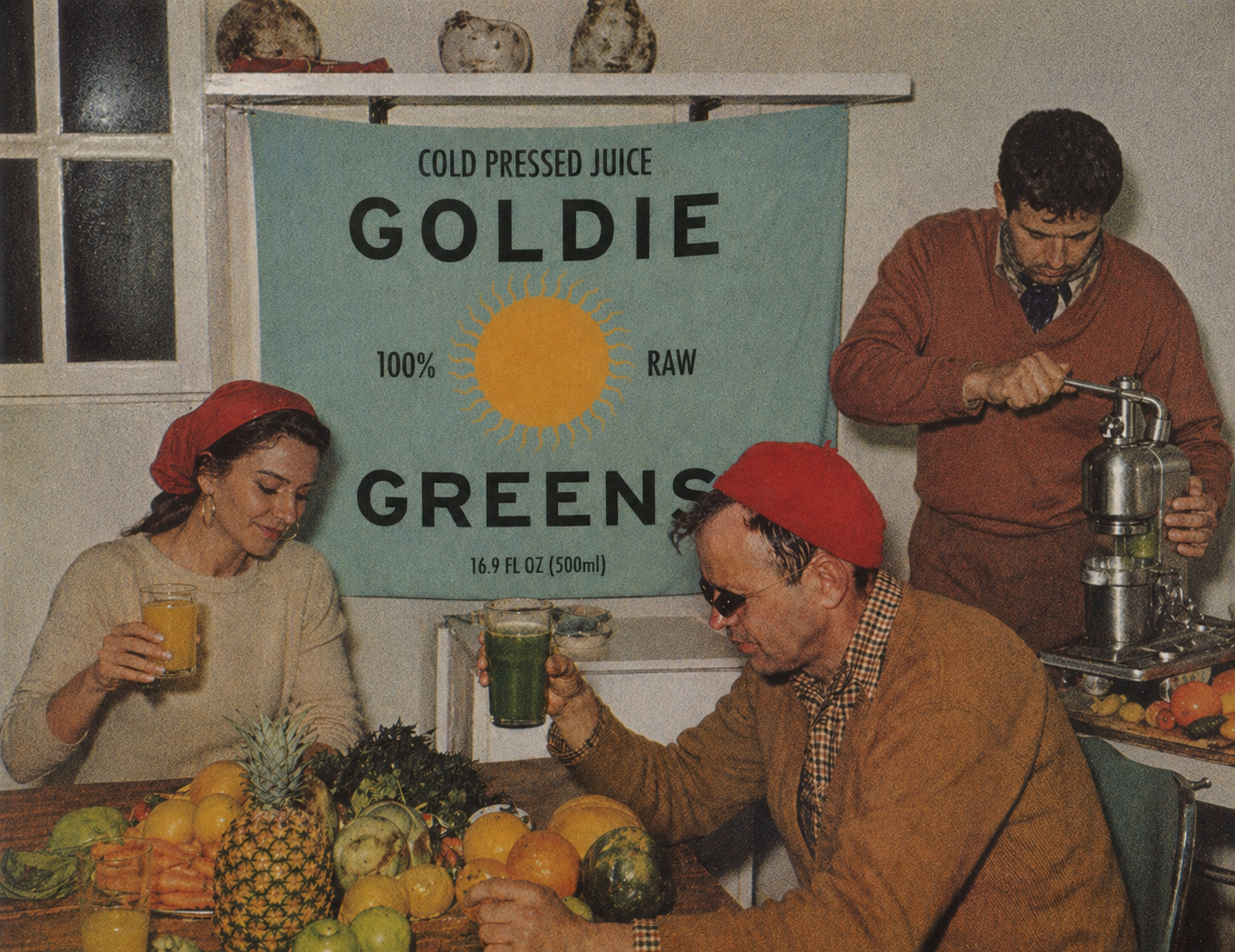 A pair of friends in red kerchiefs press fresh juice at a sun-lit kitchen counter beneath a Goldie Greens cold-pressed banner.